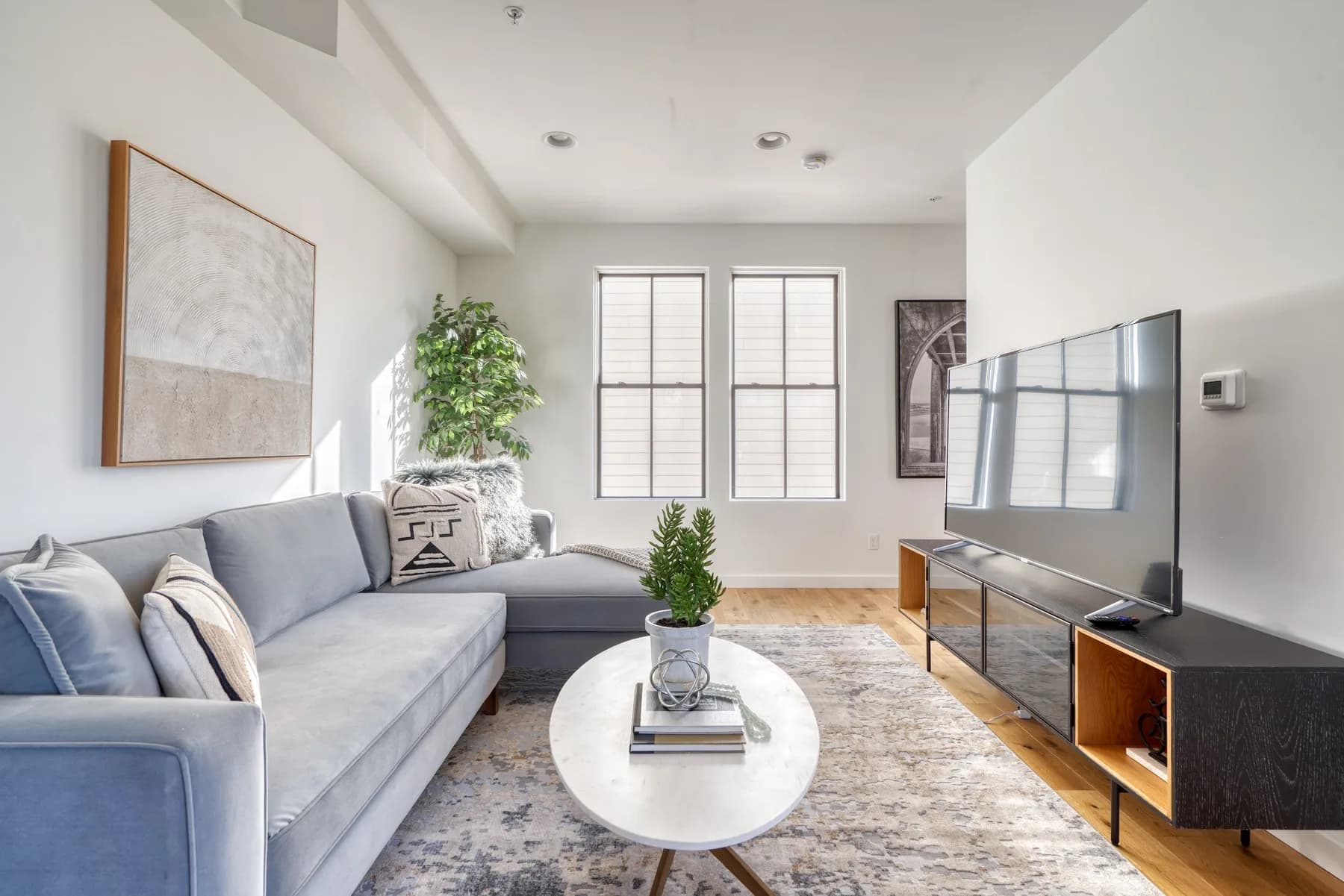 Professional home staging by Greylyn Wayne in Portland, Oregon — staged living room with gray sectional, marble coffee table, and curated art