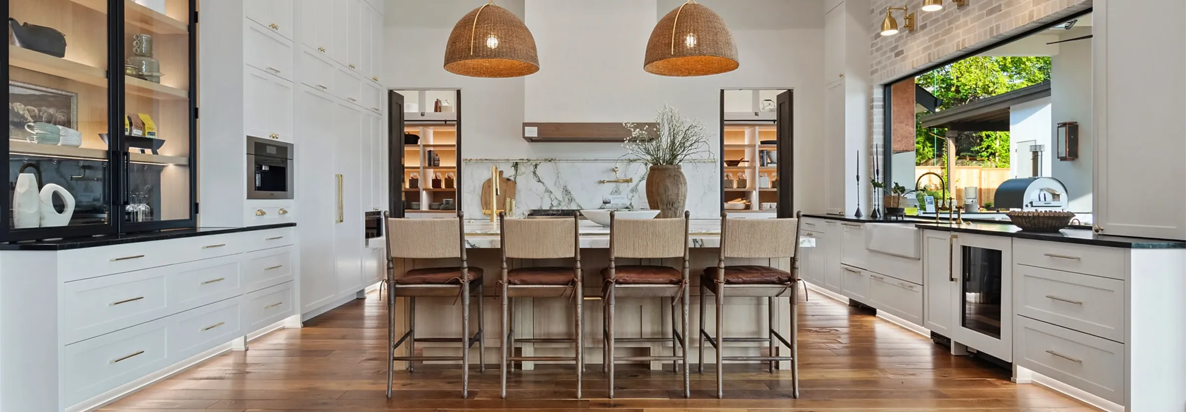 New construction model home kitchen staged by Greylyn Wayne — white cabinetry, large island with bar stools, glass-front cabinets, and brass pendant lighting in Portland, Oregon